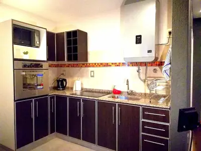 a kitchen with brown cabinets and a sink and a microwave at Altos de Chacabuco Planta Alta Apartamento temporario amoblado premium con cochera gratis in Cordoba