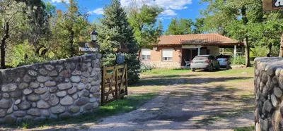 a house with a stone fence in front of a driveway at Hermoso Chalet en Nono in Nono