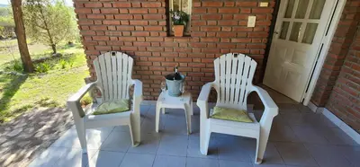 two white chairs and a table on a porch at Hermoso Chalet en Nono in Nono