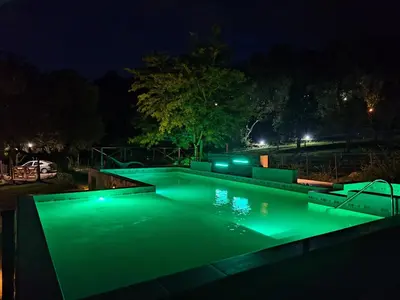 a swimming pool with green lighting at night at COSTA COM Departamentos de Montaña in Merlo