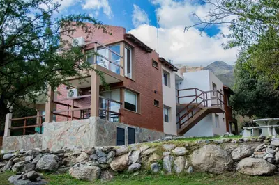 a house on a hill with a stone wall at COSTA COM Departamentos de Montaña in Merlo
