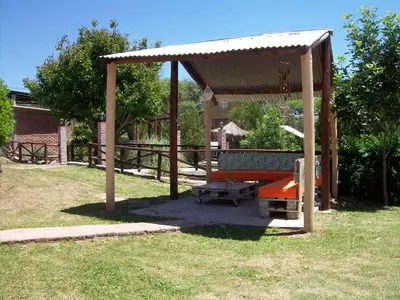 a wooden pavilion with a bench in a park at Hosteria Santa Francisca in Villa Cura Brochero