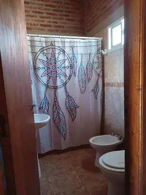 a bathroom with a shower curtain and a toilet at Hosteria Santa Francisca in Villa Cura Brochero