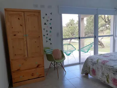 a bedroom with a bed and a dresser and a chair at COSTA COM Departamentos de Montaña in Merlo