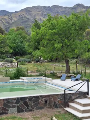 a swimming pool with two chairs and a tree at COSTA COM Departamentos de Montaña in Merlo