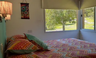 a bedroom with a bed with pillows and a window at COSTA COM Departamentos de Montaña in Merlo