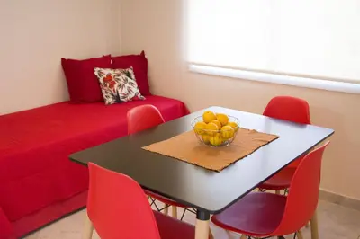 a dining room with a table with red chairs and a bowl of fruit at COSTA COM Departamentos de Montaña in Merlo