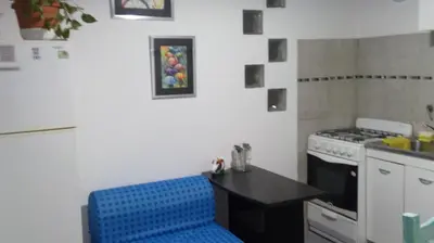 a kitchen with a stove and a blue stool at Departamento MT 2 Barrio Jardín in Cordoba