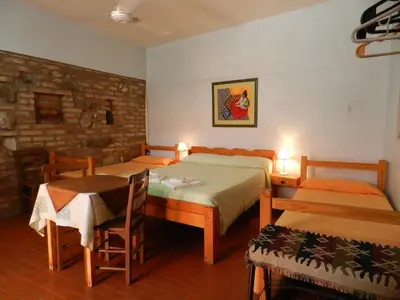 a bedroom with two beds and a table and chairs at Hostel Ctalamochita in Embalse