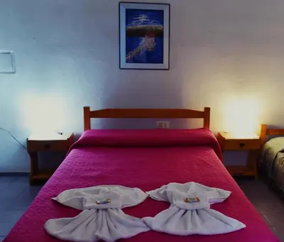 a bedroom with a red bed with two robes at Hostel Ctalamochita in Embalse