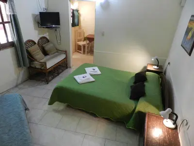 a bedroom with a green bed and a chair at Hostel Ctalamochita in Embalse