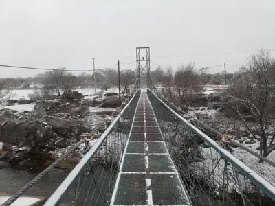 a suspension bridge over a river in the snow at Finca La Virreinita in Panaholma