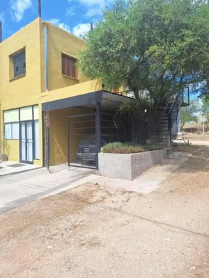 a yellow building with a car parked in the garage at Apartamento Emir in Mina Clavero