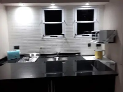 a kitchen with a sink and two windows at Apart Las Palmeras Corcovado in Villa Rumipal