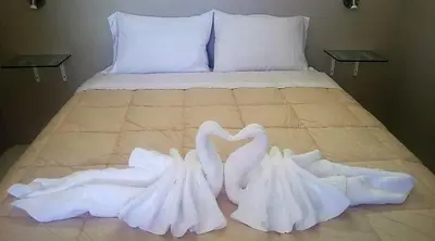 two white swans made out of towels sitting on a bed at Apart Las Palmeras Corcovado in Villa Rumipal