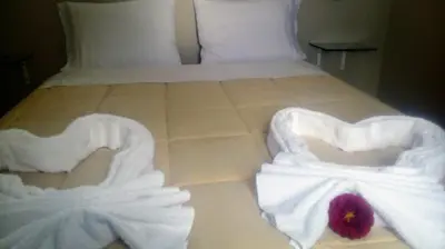 a bed with white towels and a flower on it at Apart Las Palmeras Corcovado in Villa Rumipal