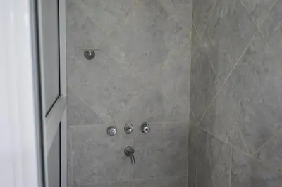 a shower with a glass door with buttons on it at Eirú Hostel in Santa Rosa de Calamuchita