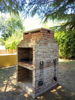 a brick oven in a yard with trees in the background at Tacuifi I - Apartamentos in Los Reartes