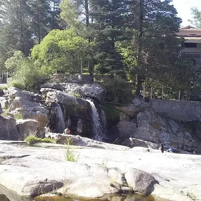 a waterfall in a park with rocks and trees at La Allandesa in Cavalango