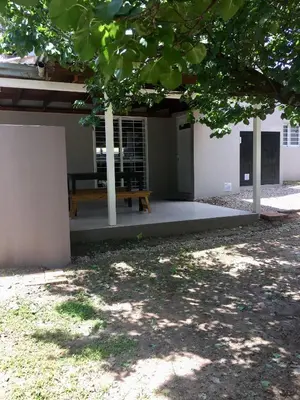 a wooden bench sitting under a building under a tree at La Franca Cabaña de Veraneo in Villa General Belgrano