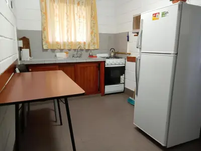a kitchen with a white refrigerator and a table at Hostería El Peregrino in Villa Cura Brochero