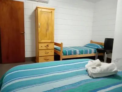 a bedroom with two beds and a dresser and a cabinet at Hostería El Peregrino in Villa Cura Brochero