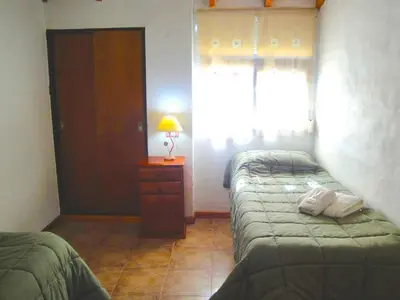 a bedroom with two beds and a table with a lamp at Chalets Los Abedules in Villa General Belgrano