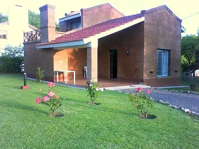 a house with two trees in front of a yard at Chalets Los Abedules in Villa General Belgrano