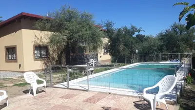 a swimming pool with white chairs next to a house at Cabañas Corazon de Maria in Merlo
