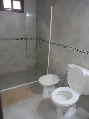 a white bathroom with a toilet and a shower at Cabañas Corazon de Maria in Merlo