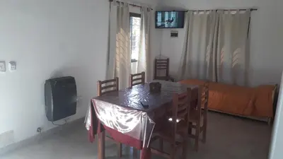 a dining room with a table and chairs and a television at Cabañas Corazon de Maria in Merlo