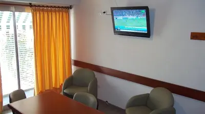 a waiting room with a table and chairs and a television at Nuna Ayni Apartments in Alta Gracia