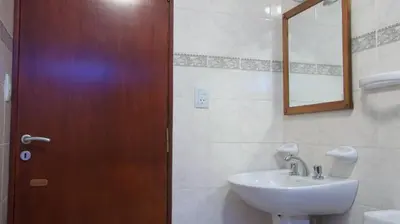 a bathroom with a wooden door and a sink at Nuna Ayni Apartments in Alta Gracia