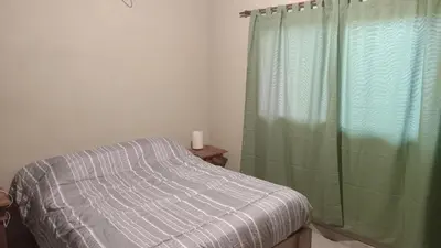 a bedroom with a bed and a green shower curtain at Cabañas Kangarú in Santa Rosa de Calamuchita