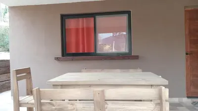 a mirror on a wall with a table and a chair at Cabañas Kangarú in Santa Rosa de Calamuchita