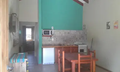 a kitchen with a table and a counter top at Cabañas Kangarú in Santa Rosa de Calamuchita