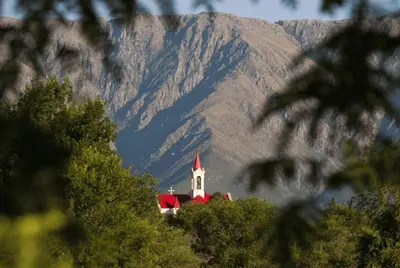 a church with a red roof in front of a mountain at BoraBora in Nono