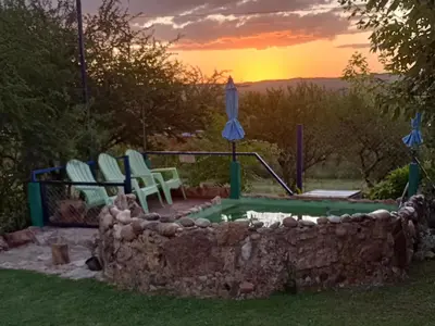 a swimming pool with two chairs and an umbrella at La Pirca in Nono
