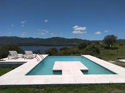 a swimming pool with two chairs and a body of water at Un Buen Lugar in Villa Parque Siquiman