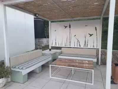 a patio with two benches and a table and birds on a wall at Un Buen Lugar in Villa Parque Siquiman