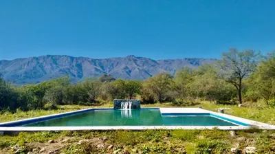 a swimming pool in a field with mountains in the background at CampoAlto Suites in San Javier
