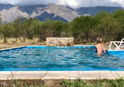 a woman in a swimming pool with mountains in the background at CampoAlto Suites in San Javier