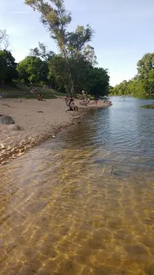 a body of water with people sitting on the beach at El Tatu in La Bolsa