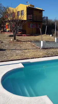 a blue swimming pool in front of a house at Casa en Balcón de Mallín, Mirador del Lago in Bialet Massé