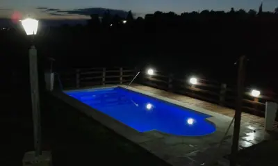 a large blue swimming pool at night with lights at Casa en Balcón de Mallín, Mirador del Lago in Bialet Massé