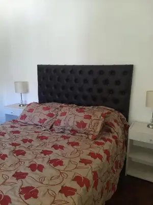 a bedroom with a bed with a red floral bedspread at Excepcional dpto frente a Plaza de la Intendencia in Cordoba