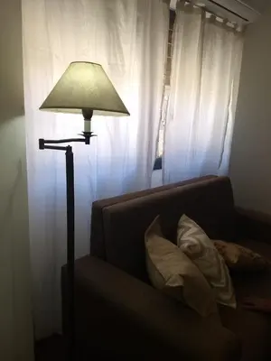 a lamp sitting next to a couch in front of a window at Excepcional dpto frente a Plaza de la Intendencia in Cordoba