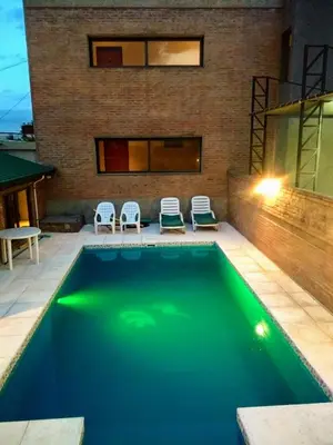 a swimming pool with two chairs and a building at Casa Decla in Villa Carlos Paz