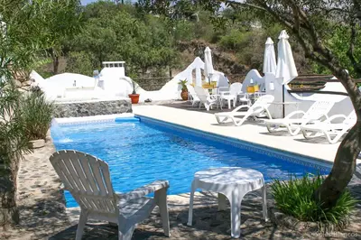 a pool with white chairs and a table and chairs at Soles Blancos Serranita in Alta Gracia