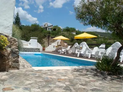 a swimming pool with white chairs and umbrellas at Soles Blancos Serranita in Alta Gracia